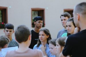 Teenagers gathered outdoors engaged in a lively discussion, fostering communication and learning.