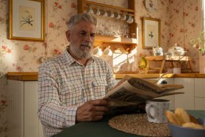 Senior man enjoying morning newspaper in a warm, floral-themed kitchen