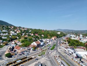Aerial shot of a suburban landscape featuring housing, roads, and a tram in a sunny cityscape.
