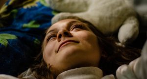 Close-up portrait of a woman lying indoors, looking relaxed and content.
