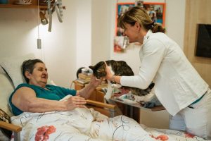 A caregiver shares a gentle moment with a cat and a senior resident, fostering connection and happiness in a retirement