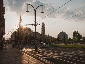 Charming sunset over a European city with historic architecture and street lamps casting shadows.