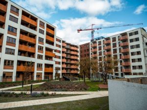 Newly built apartment complex with crane under blue sky, modern architecture.