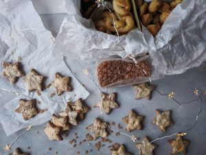 Top view of delicious star-shaped cookies with fairy lights on a gray background, perfect for holiday decorations.