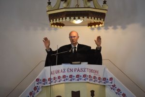 A pastor delivers a sermon inside a church in Vásárosnamény, offering blessings from the pulpit.